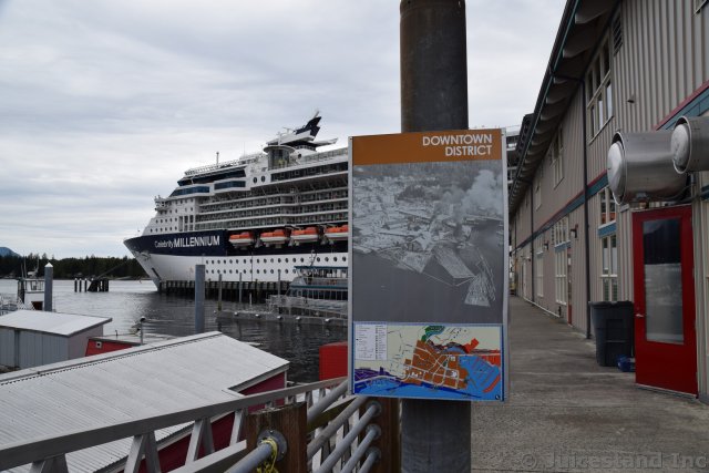 Ketchikan Downtown District Sign on Salmon Landing area with Cruise Ship in the Background
